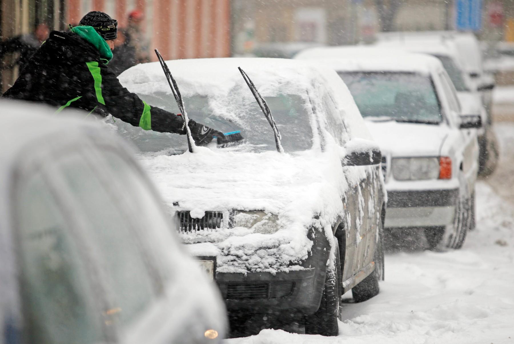 Čovek čisti auto od snega