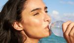 Žena pije vodu iz plastične flaše