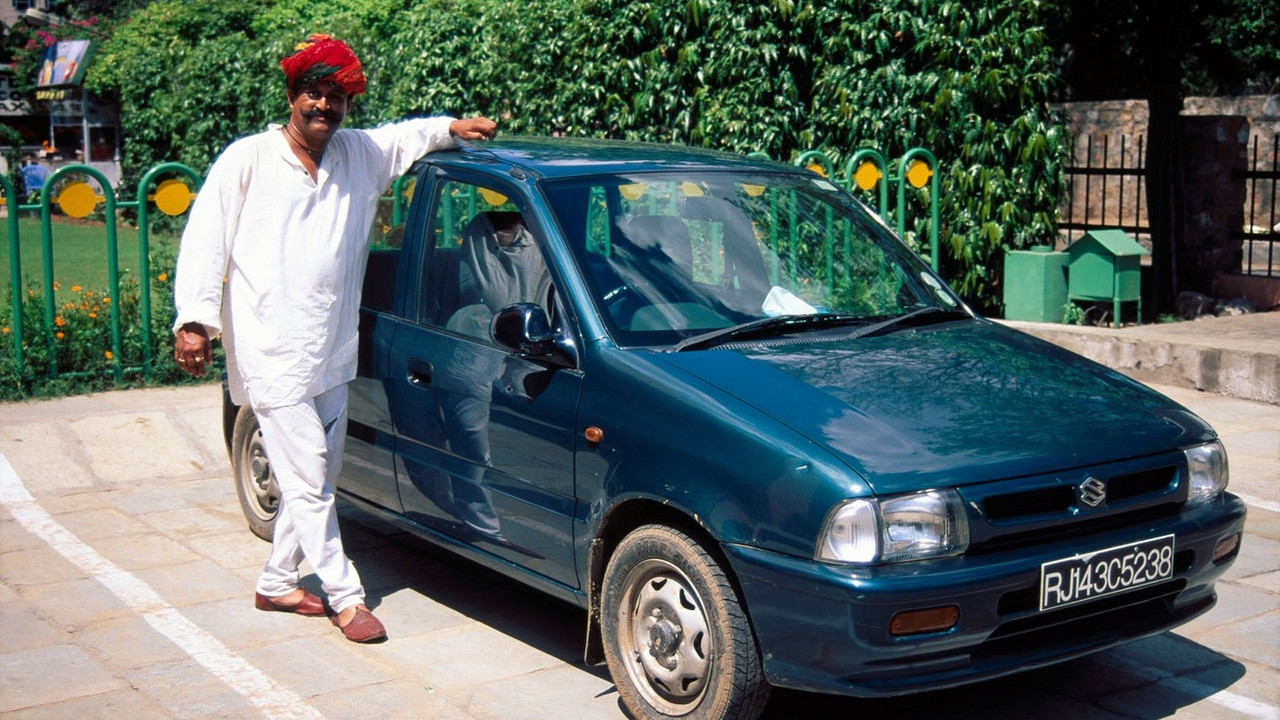 Indijac stoji pored svog automobila