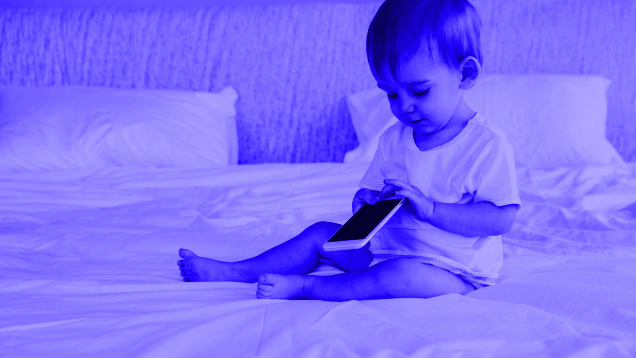 Dete u krevetu sa mobilnim telefonom